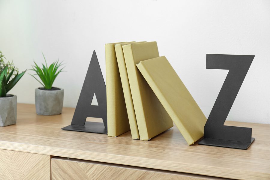 Black metal A and Z bookends holding a row of books on a desk
