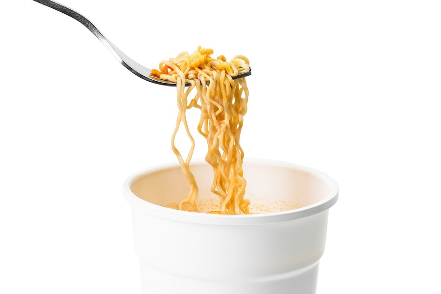 A fork lifting noodles out of an instant noodle cup