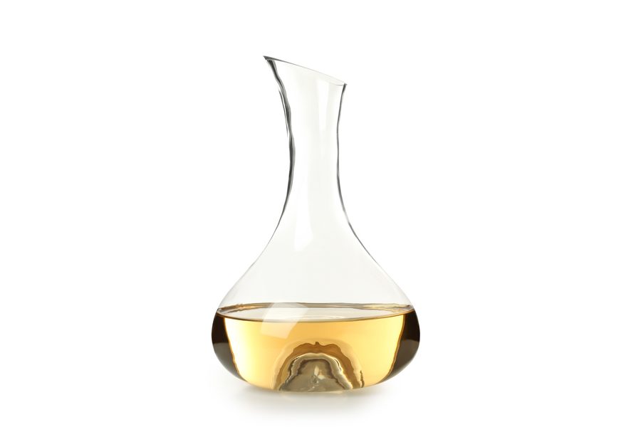 A crystal wine decanter with a splash of white wine in it