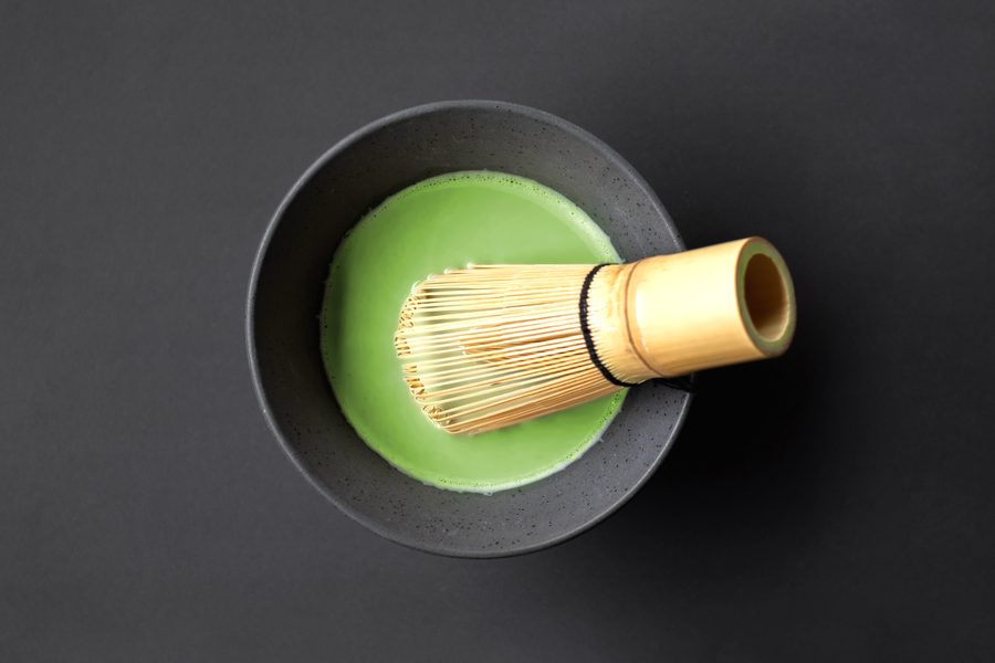 A bowl of matcha with a bamboo whisk