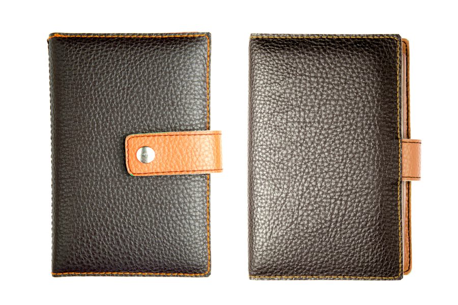 A brown pebbled faux-leather refillable notebook with a snap strap, closed