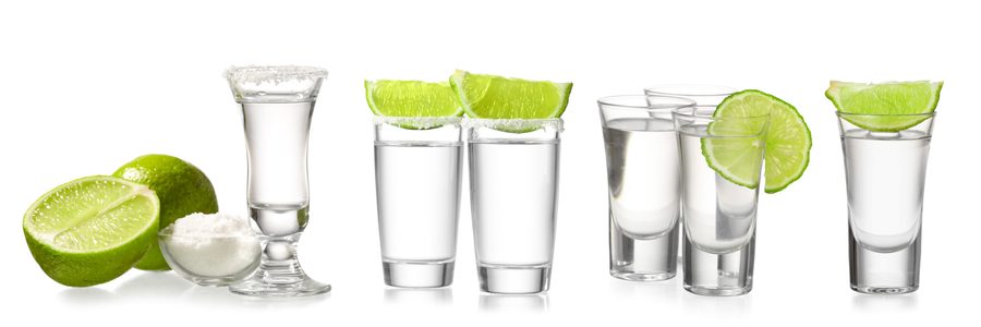 Tequila shot glasses with lime and salt on a white background